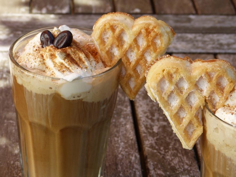 Cinnamon-topped latte with whipped cream and heart-shaped waffles.