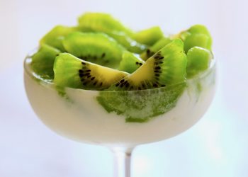 Kiwi slices topping creamy dessert in a clear glass dish.