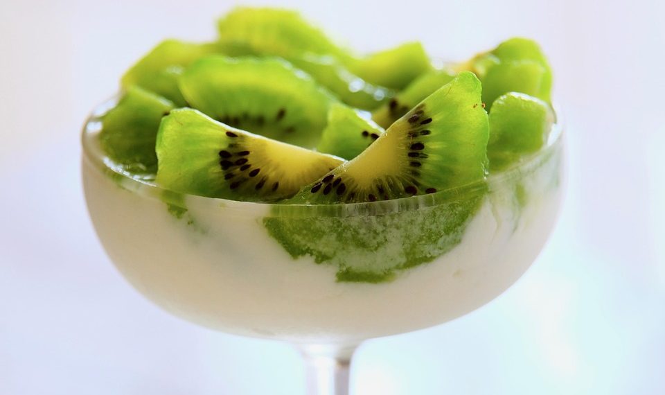 Kiwi slices topping creamy dessert in a clear glass dish.