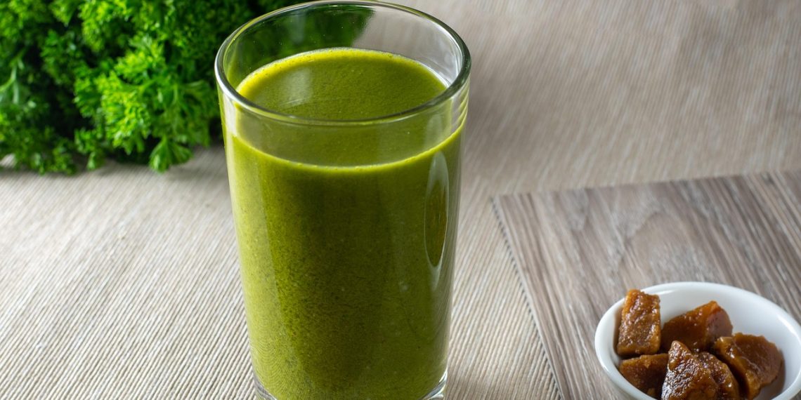 Green smoothie with parsley and figs on a wooden table.
