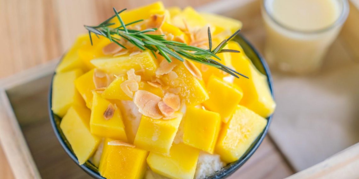 Mango bingsu topped with almonds and rosemary, served with condensed milk.