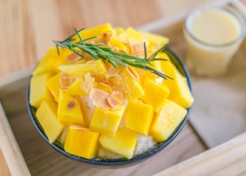 Mango bingsu topped with almonds and rosemary, served with condensed milk.