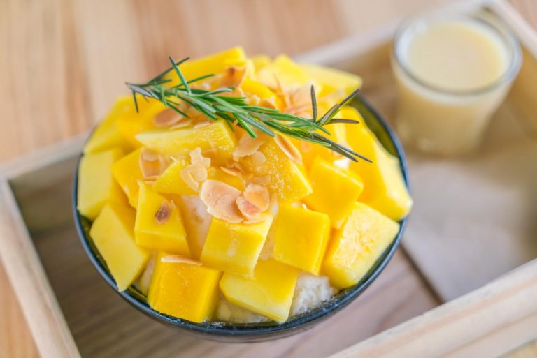 Mango bingsu topped with almonds and rosemary, served with condensed milk.