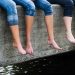 Bare feet dangling over concrete ledge.
