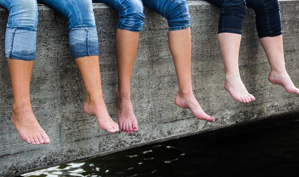 Bare feet dangling over concrete ledge.