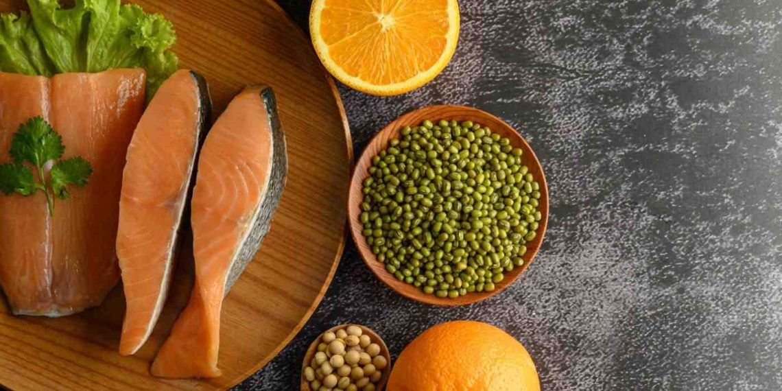 Fresh salmon with orange slices and mung beans on a wooden platter.