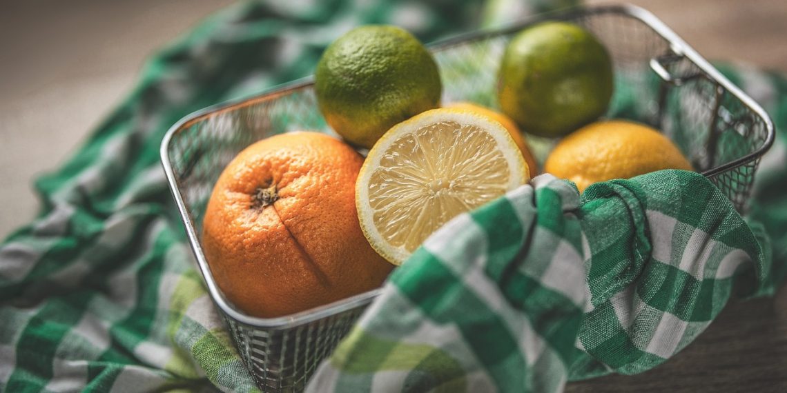 Mixed citrus fruits in a basket with colorful checkered cloth.