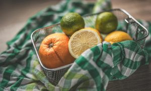Mixed citrus fruits in a basket with colorful checkered cloth.
