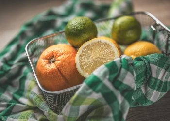 Mixed citrus fruits in a basket with colorful checkered cloth.