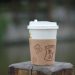 Cup of coffee on wooden post outdoors.