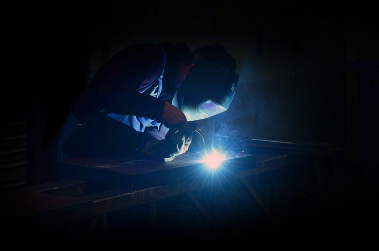 Welder working at night with bright sparks flying.