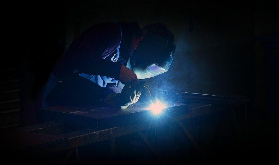 Welder working at night with bright sparks flying.