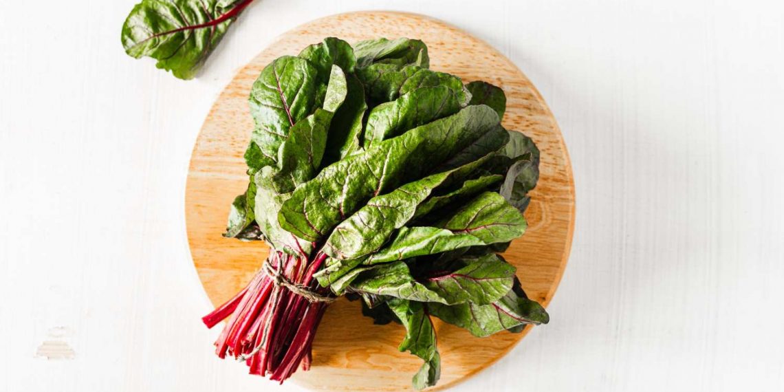 Fresh Swiss chard on a wooden cutting board.