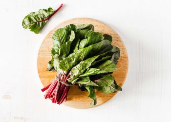 Fresh Swiss chard on a wooden cutting board.