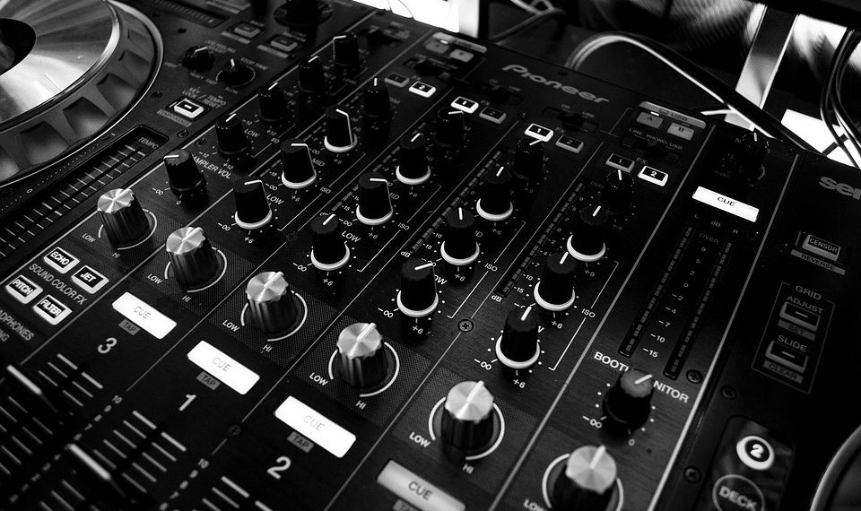 DJ mixing console with multiple controls and dials, used for music production.