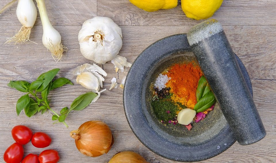 Fresh ingredients and spices with mortar and pestle on wooden surface.