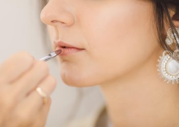 Applying lipstick with a precise brush technique.