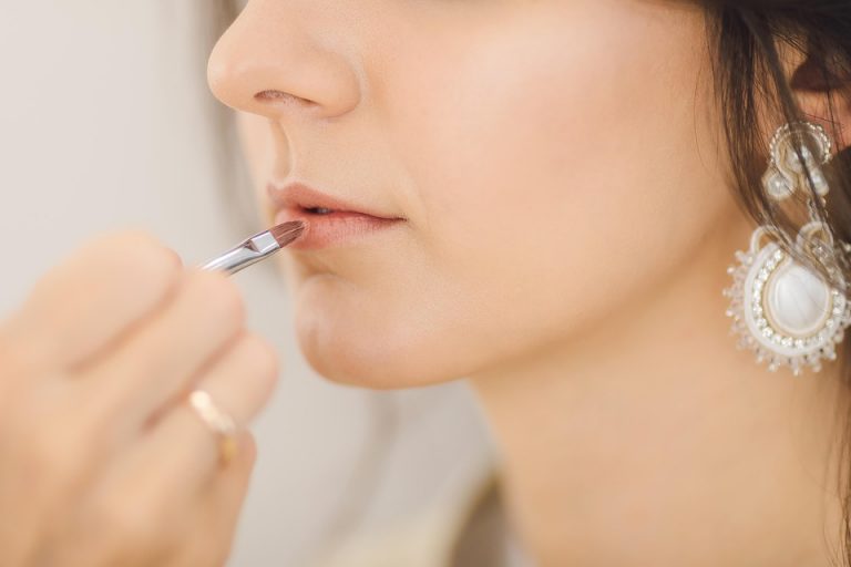 Applying lipstick with a precise brush technique.