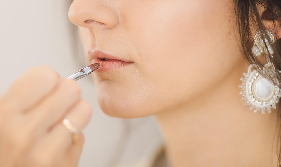 Applying lipstick with a precise brush technique.