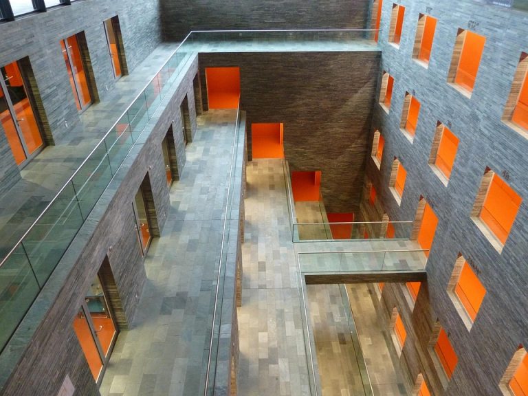 Modern atrium with orange accents and glass walkways, showcasing stylish architecture.