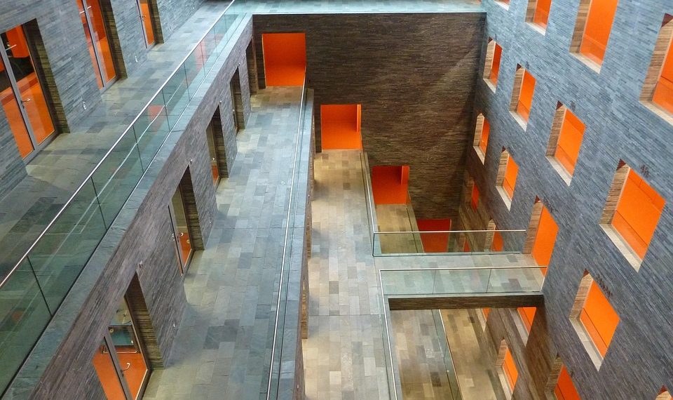 Modern atrium with orange accents and glass walkways, showcasing stylish architecture.