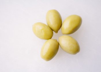 Green olives arranged on a white surface
