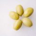 Green olives arranged on a white surface
