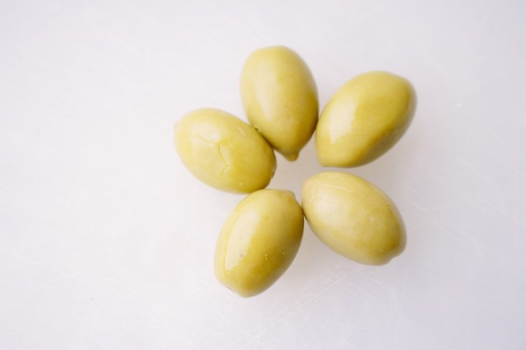 Green olives arranged on a white surface