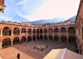 Ancient courtyard with arches and mountain view in the background.