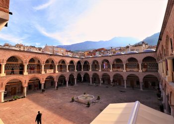Ancient courtyard with arches and mountain view in the background.