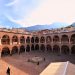 Ancient courtyard with arches and mountain view in the background.