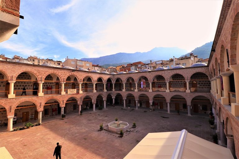 Ancient courtyard with arches and mountain view in the background.