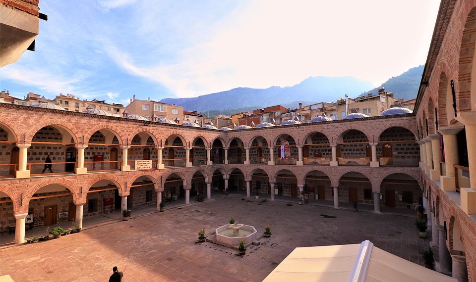 Ancient courtyard with arches and mountain view in the background.