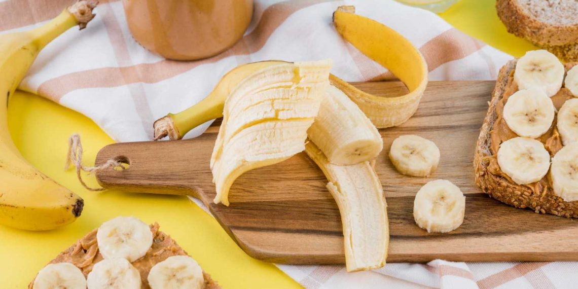 Sliced bananas on peanut butter toast with whole bananas and spread.