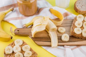 Sliced bananas on peanut butter toast with whole bananas and spread.