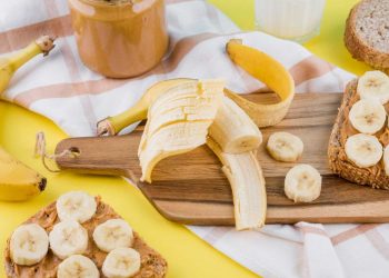 Sliced bananas on peanut butter toast with whole bananas and spread.