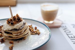 Stack of pancakes topped with nuts and served with coffee.