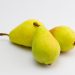Three fresh yellow pears on a white background.