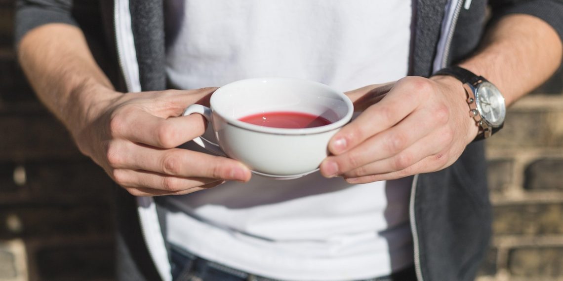 Hands holding a cup of red tea outdoors
