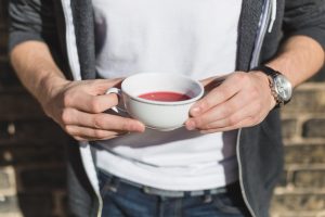 Hands holding a cup of red tea outdoors