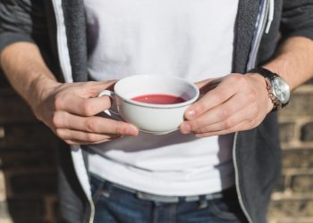 Hands holding a cup of red tea outdoors
