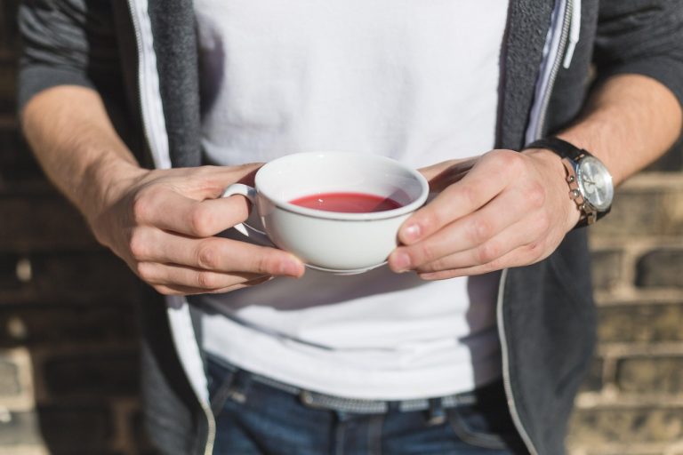 Hands holding a cup of red tea outdoors