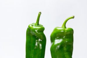 Two fresh green bell peppers on a white background.