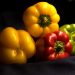 Mixed bell peppers on dark fabric showcasing fresh, vibrant colors.