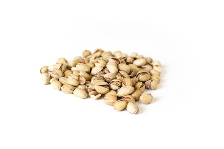 Pile of roasted pistachios on white background.
