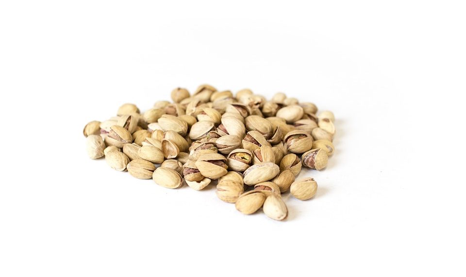 Pile of roasted pistachios on white background.