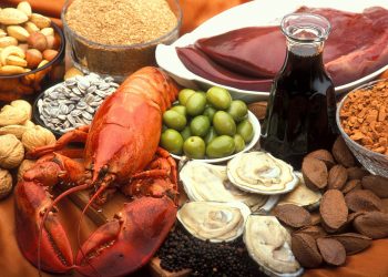 Assorted seafood, nuts, and olives with oil displayed on a table.