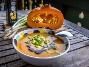 Pumpkin soup garnished with green onions and drizzled with pumpkin seed oil.