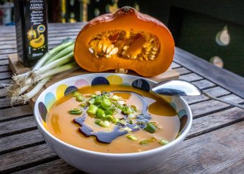 Pumpkin soup garnished with green onions and drizzled with pumpkin seed oil.