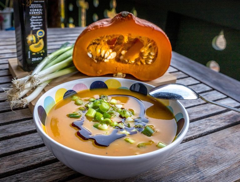 Pumpkin soup garnished with green onions and drizzled with pumpkin seed oil.